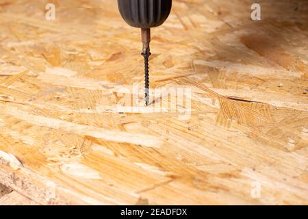 Screw and screwdriver on a chipboard sheet. Carpentry and construction tools with copyspace for text. Stock Photo