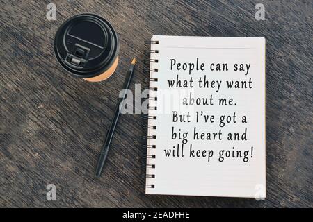 Motivational and inspirational quote on notepad with disposable coffee cup and pen on wooden table Stock Photo