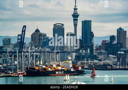 Emirates Team New Zealand's Te Rehutia foiling monohull sails in front of the Auckland central business district and waterfront and Port of Auckland w Stock Photo