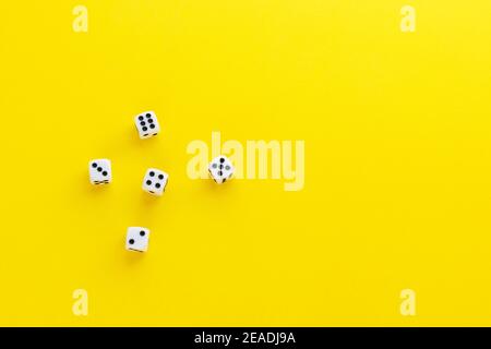 Five dice showing different sides on yellow background. Playing cube with numbers. Items for board games. Flat lay, top view with copy space. Stock Photo