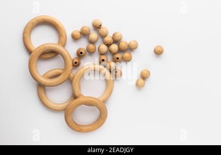 Five wooden rings and beads on white background. Natural wood baby teether. Eco-friendly children toy. Top view, flat lay with copy space. Stock Photo