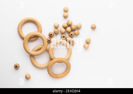 Five wooden rings and beads on white background. Natural wood baby teether. Eco-friendly children toy. Top view, flat lay with copy space. Stock Photo
