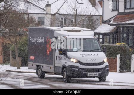 Merton, London, UK. 9 February 2021. Heavier morning snowfall in south London lies on untreated suburban streets but gritted main roads remain clear with no traffic holdups. A Tesco home delivery van at work in the snow. Credit: Malcolm Park/Alamy Live News. Stock Photo