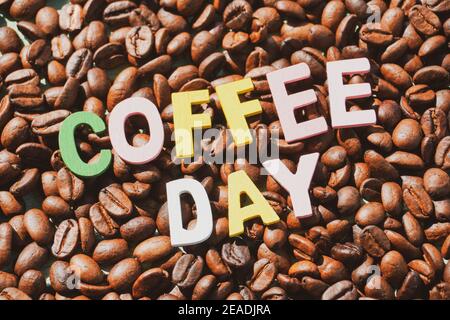 Coffee Day alphabets form on roasted coffee beans background. Stock Photo