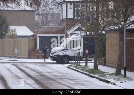 Merton, London, UK. 9 February 2021. Heavier morning snowfall in south London lies on untreated suburban streets but gritted main roads remain clear with no traffic holdups. A Tesco home delivery van at work in the snow. Credit: Malcolm Park/Alamy Live News. Stock Photo