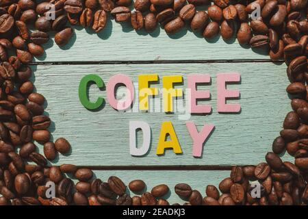 Coffee Day alphabets form on roasted coffee beans background. Stock Photo