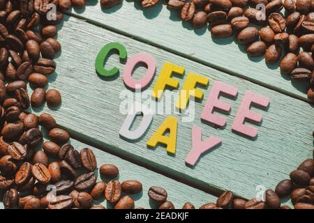 Coffee Day alphabets form on roasted coffee beans background. Stock Photo