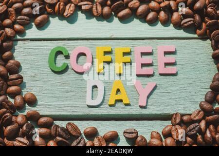Coffee Day alphabets form on roasted coffee beans background. Stock Photo