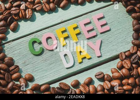Coffee Day alphabets form on roasted coffee beans background. Stock Photo