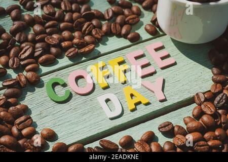 Coffee Day alphabets form on roasted coffee beans background. Stock Photo
