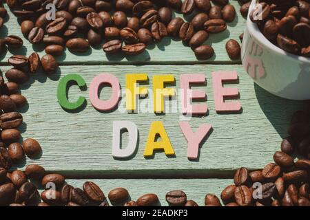 Coffee Day alphabets form on roasted coffee beans background. Stock Photo