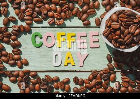 Coffee Day alphabets form on roasted coffee beans background. Stock Photo