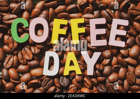 Coffee Day alphabets form on roasted coffee beans background. Stock Photo