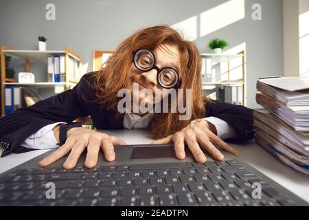 Funny nerd in glasses using laptop and searching for information on the Internet Stock Photo