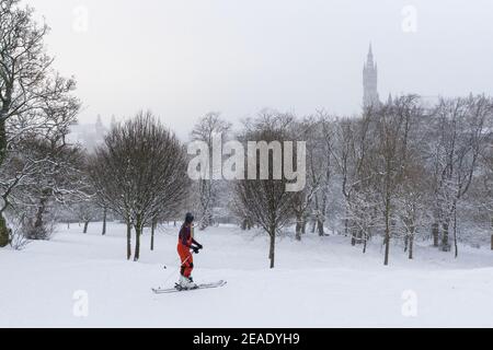 People enjoying winter snow in Kelvingrove Park Glasgow UK. Children on sledge. Skiing in park. Cyclist. Winter storm. Glasgow University. Stock Photo