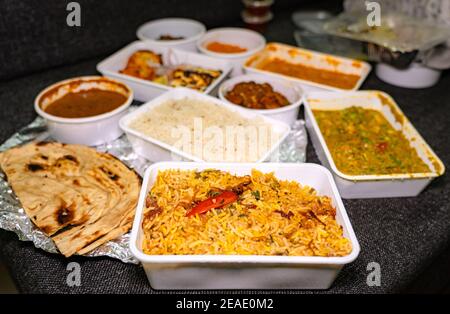 Selective focus of Vegetable Biryani in a white takeout box. Many foods in takeout boxes blurred in the background. Stock Photo