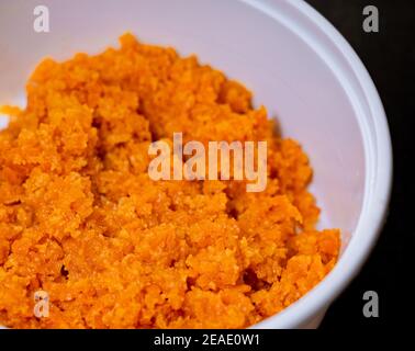 Close up of Carrot Halwa or Gajar ka halwa in a white takeout box on a black background. Stock Photo