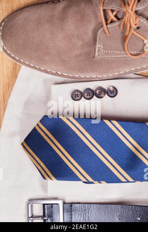 Close-up of men's Summer jacket and sand-coloured shoe with a tie and belt. Stock Photo