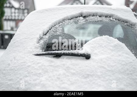 Rear windscreen wiper cleaning snow from back window of small car windscreen on fresh icy day early morning powder deep snowfall Stock Photo