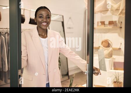 African American entrepreneur smiling while standing at her shop door Stock Photo
