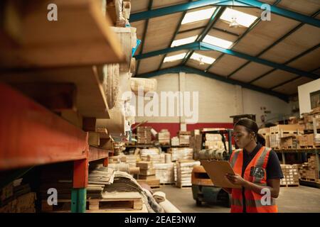 Young African female warehouse worker checking shelves of stock Stock Photo