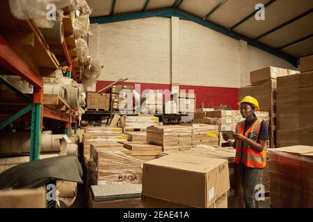 African female warehouse worker checking inventory with a digital tablet Stock Photo
