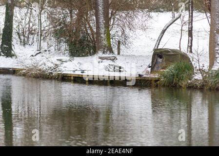 Fishing lake in Priory Park in Southend on Sea, Essex, UK, with snow from Storm Darcy, with fishing tent and rod set up. Freezing conditions Stock Photo