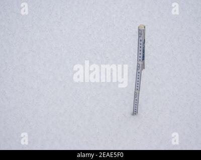 Measure the snow depth with a folding rule Stock Photo