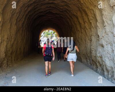 Two women passing through a tunnel in the mountains of the natural park of the Gaitanes Gorge in Malaga, on a sunny day. Stock Photo