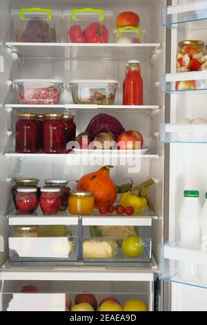 Variety glass jars homemade pickled vegetables and other products stand in fridge. Fermented healthy natural food concept. Stock Photo