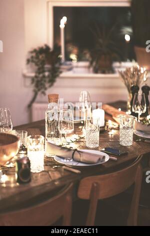 Candlelit dining table and chairs set up with glasses and tableware for an evening dinner party Stock Photo