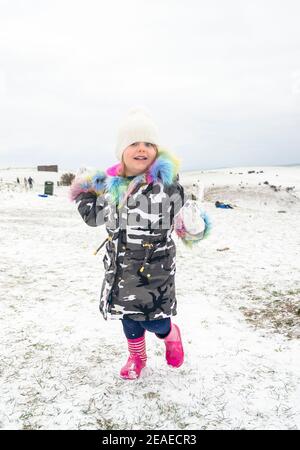 Brighton UK 9th February 2021 - Four year old Isabella enjoys making snowballs in the snow at Devils Dyke on the South Downs Way just north of Brighton today as some parts of Britain experience the coldest day of winter so far : Credit Simon Dack / Alamy Live News Stock Photo
