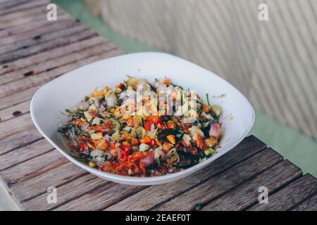 Sambal Matah. Traditional raw chili and lemongrass relish from Bali. Plated on a white bowl. Stock Photo