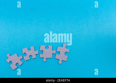 Puzzle pieces blank about to connect on bright blue flat lay background for team work, unity, completion concepts in business, life and education. Stock Photo