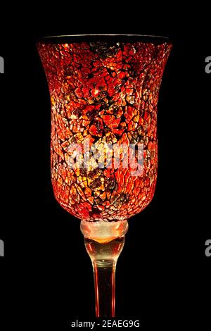 Light shining through a beautiful glass vase with a red and gold mosaic pattern. Isolated on black Stock Photo