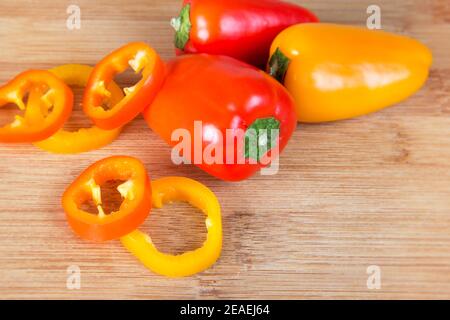 Small red and yellow peppers in cutting board, realistic approach to imperfect food ingredients, close up of small red and yellow peppers on a wooden Stock Photo