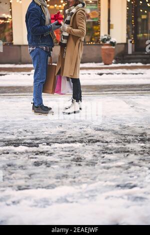 Caring man and woman exchanging Christmas presents outdoors Stock Photo
