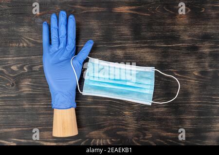 Mannequin hand wearing a disposable glove and holding a medical mask. During covid19 quarantine. Stock Photo