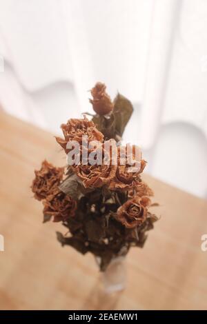 Vertical shot of beautiful dried roses in a vase on the table Stock Photo