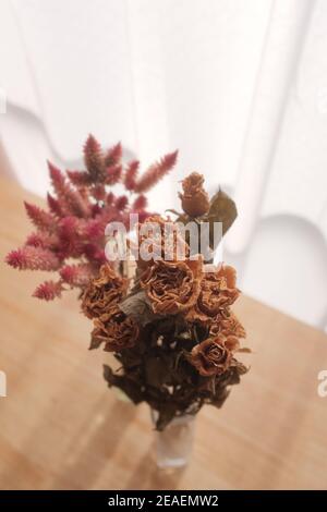 Vertical shot of beautiful dried roses and astilbe branches in a vase on the table Stock Photo