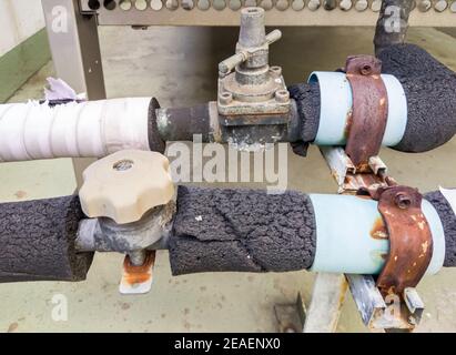 Old control valve on the metal pipeline with the insulation of the air ventilation unit in the air conditioning system, on the top of the office build Stock Photo
