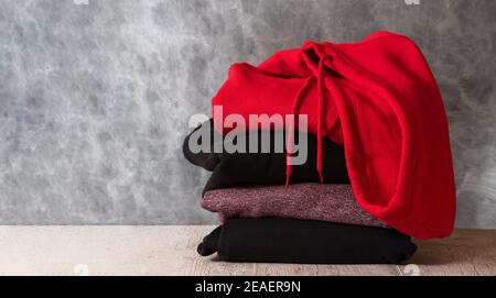 Stack of hooded sweatshirts and hoodie on gray background. Copy space Stock Photo