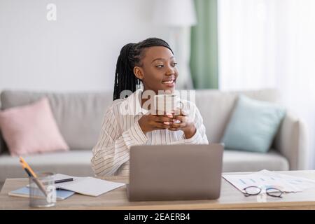 Attractive black woman freelancer having coffee break Stock Photo