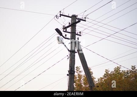 old stone pillar with lamp and wires on the white sky background Stock Photo
