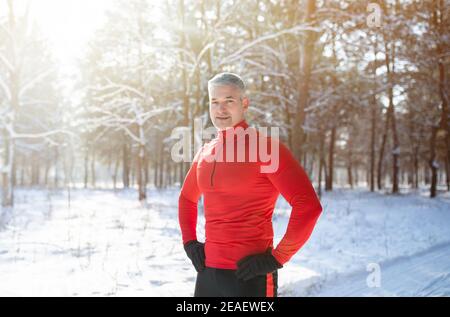 Running fitness during winter. Portrait of sporty senior man taking break from his jogging workout at snowy park Stock Photo
