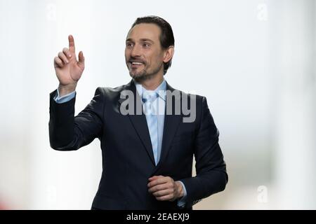 Mature businessman touching invisible virtual screen. Stock Photo