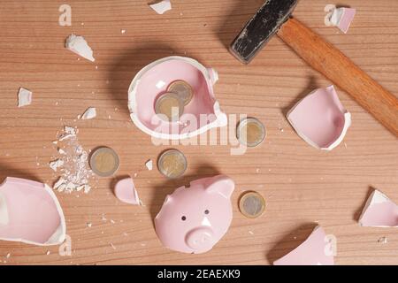 broken Piggy bank smashed into pieces - flat lay with hammer and small or loose change euro coins Stock Photo