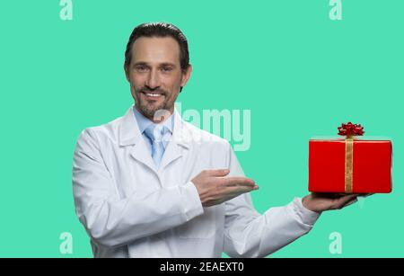 Portrait of mature doctor presenting red gift box. Stock Photo