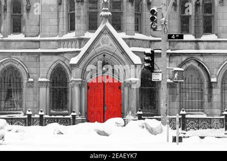 Red church door in snowy black and white winter street scene on 4th Avenue in the East Village of New York City NYC Stock Photo