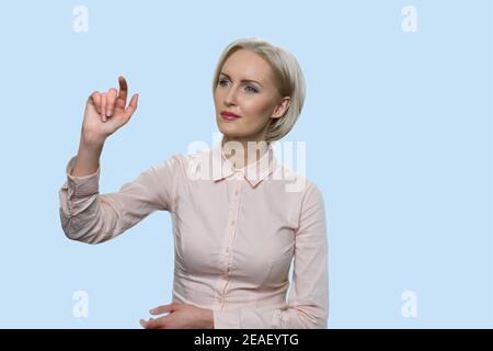 Middle-aged woman is pressing invisible touchscreen. Stock Photo